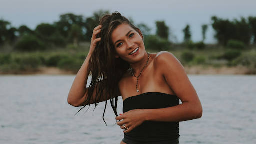 Young woman playing with hair with water in background