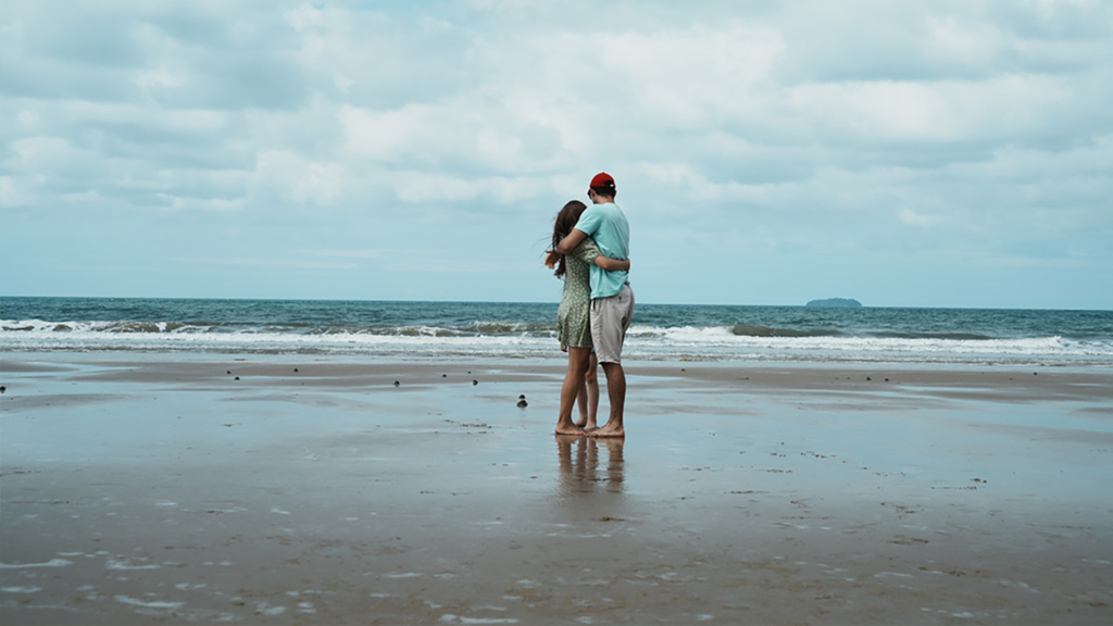 Young couple hugging on beach on a cloudy day